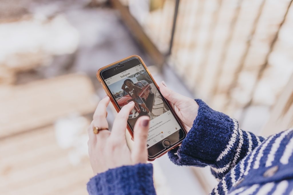 A person holds a cell phone and scrolls through instagram