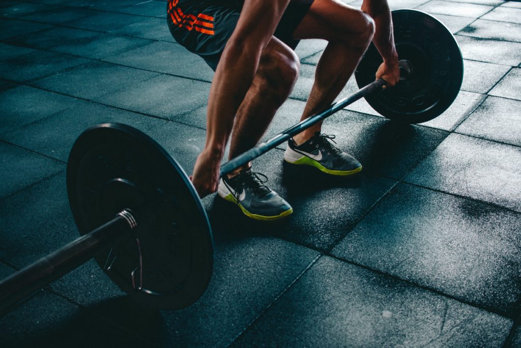 Person squats down to lift dumbbells